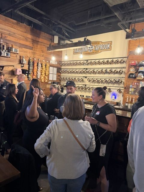 Attendees chatting in front of the Raccoon Taproom mug wall at Work The Room in Collingswood