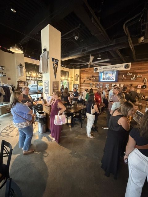 Wide view of a busy Work The Room crowd networking across the Raccoon Taproom floor